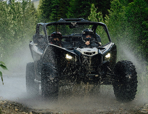 Side-by-side off-road buggy splashing through a creek near Whistler