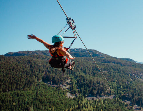 Guest flying a dual zipline over Whistler backcountry with Superfly Ziplines